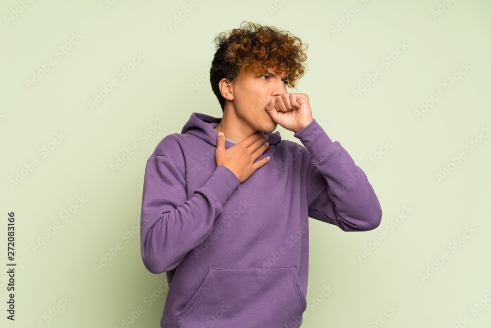 Young african american man over isolated green wall is suffering with cough and feeling bad
