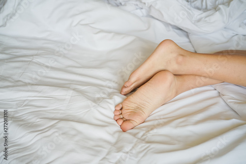 young woman's feet on white bed
