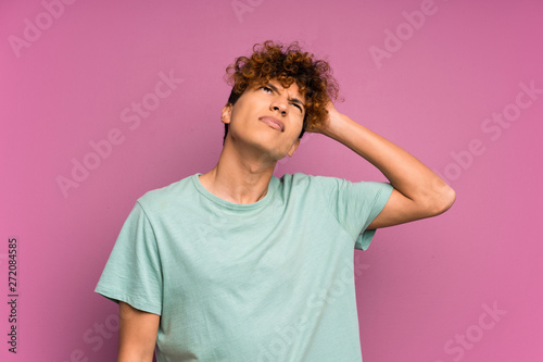 Young african american man over isolated purple wall having doubts and with confuse face expression