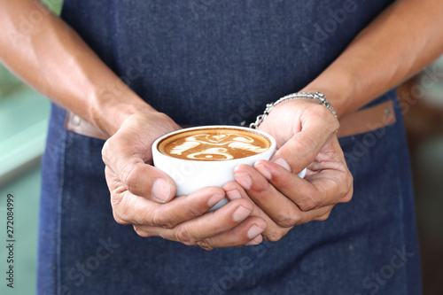 Barista hand holding coffee latte art with pattern the bell in coffee shop