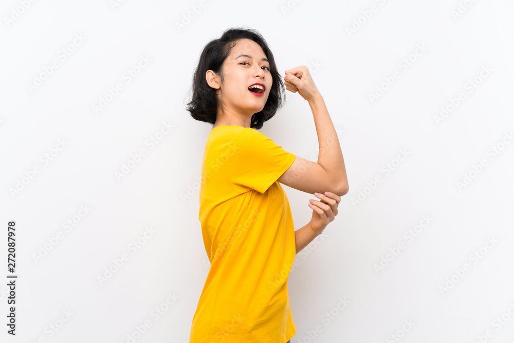 Asian young woman over isolated white background doing strong gesture Asian young woman over isolated white background doing strong gesture