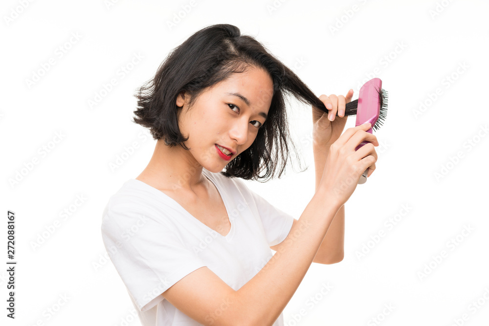 Asian young woman over isolated background with hair comb Asian young woman over isolated background with hair comb