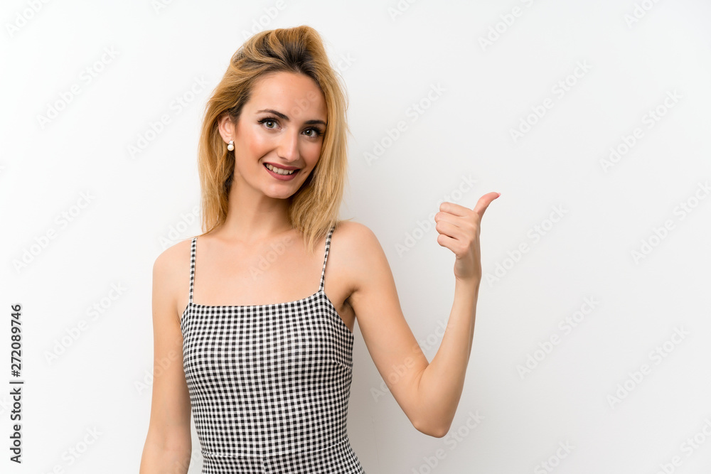 Young blonde woman over isolated white pointing to the side to present a product Young blonde woman over isolated white pointing to the side to present a product