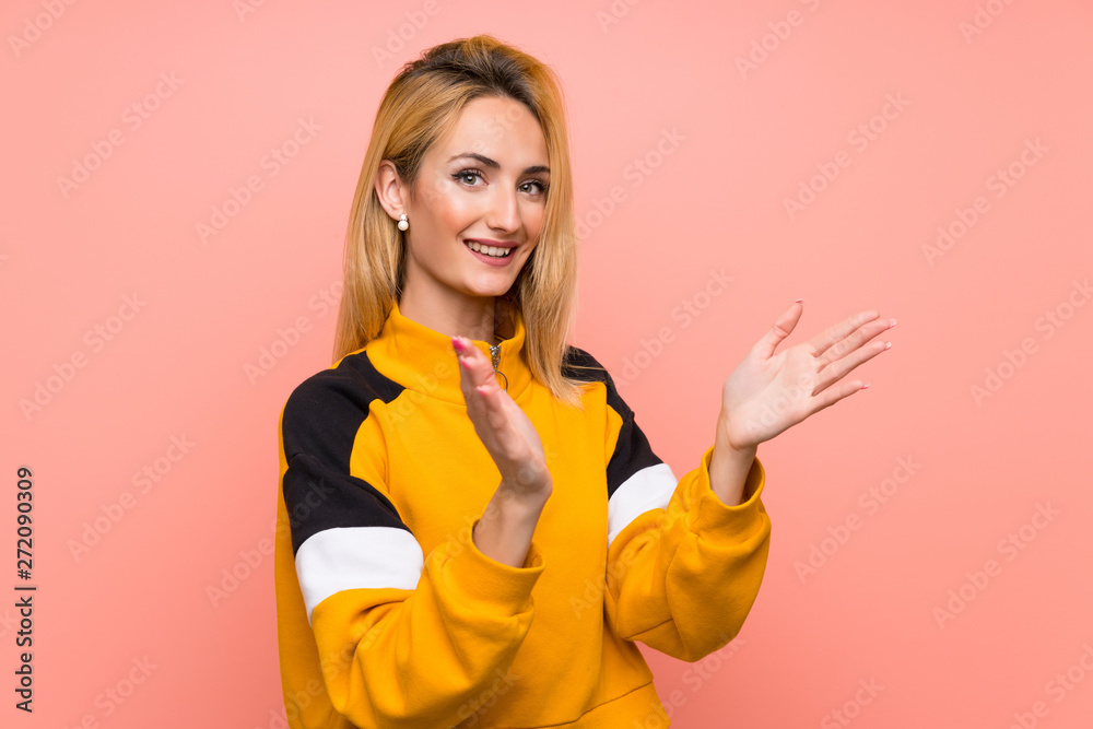 Young blonde woman over isolated pink background applauding after presentation in a conference Young blonde woman over isolated pink background applauding after presentation in a conference