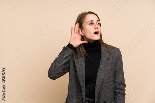 Young woman over isolated wall listening something