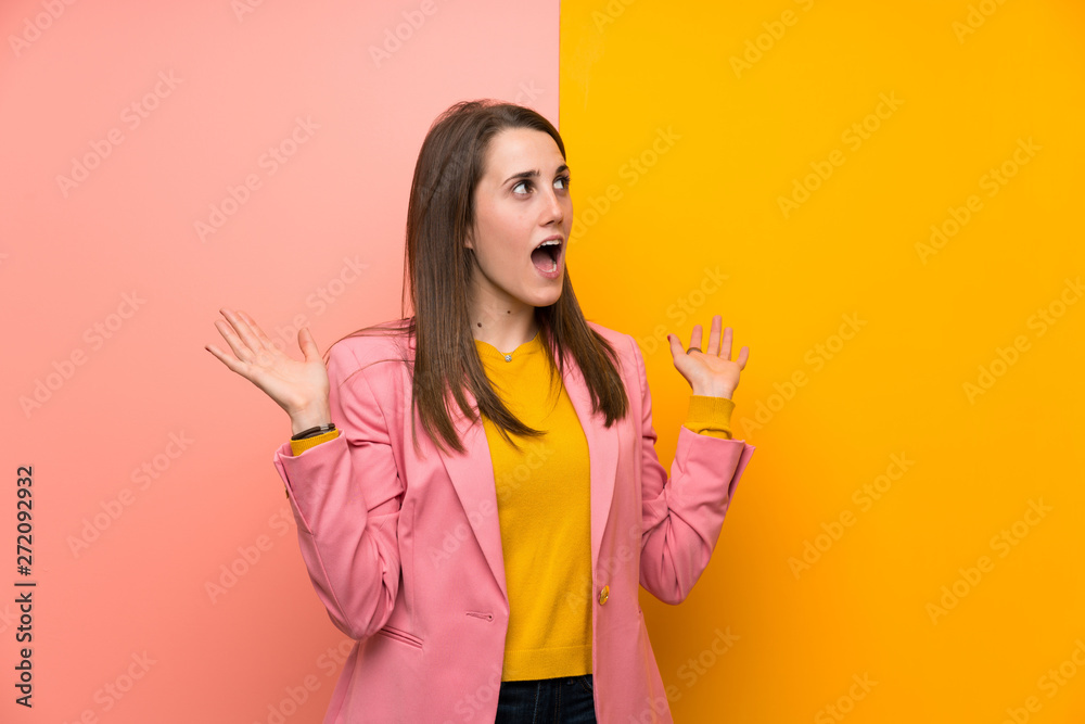 Young woman with pink suit over colorful background with surprise facial expression Young woman with pink suit over colorful background with surprise facial expression