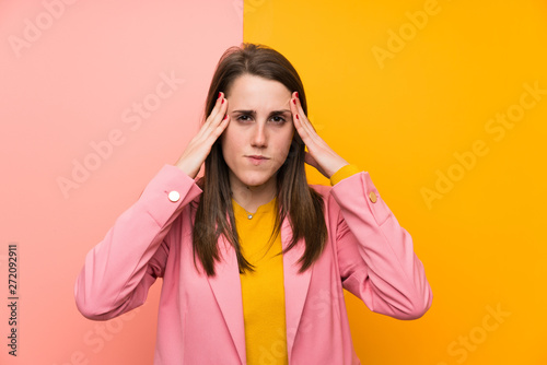 Young woman with pink suit over colorful background unhappy and frustrated with something. Negative facial expression