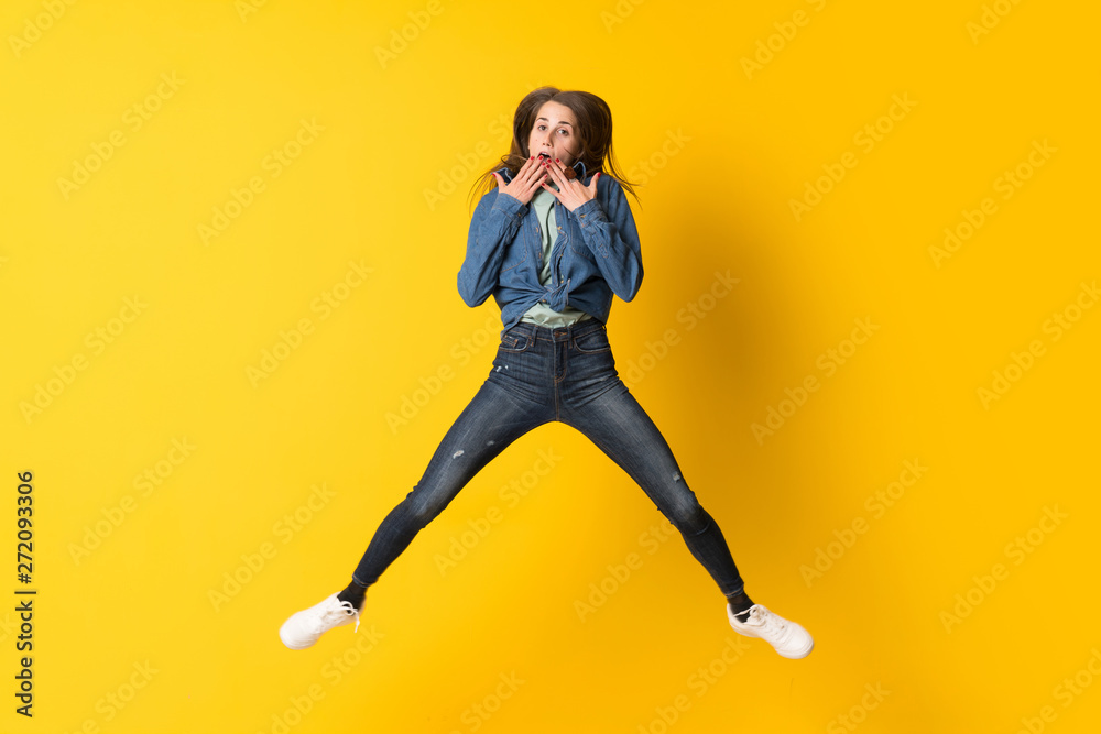 Young woman jumping over yellow background