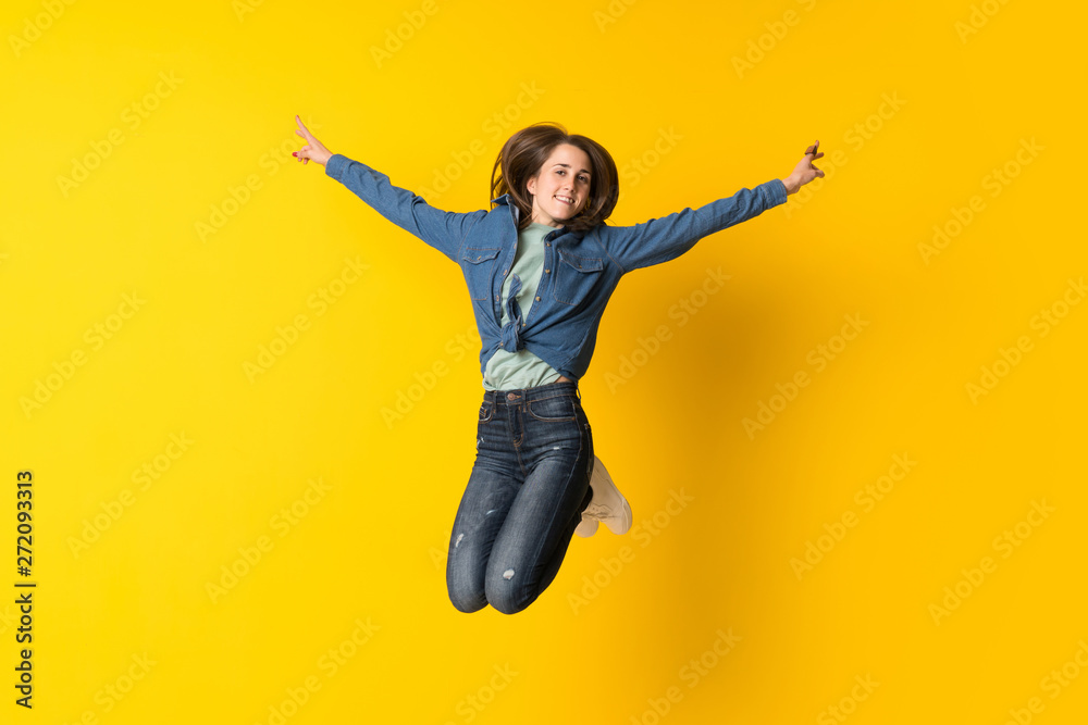 Young woman jumping over yellow background