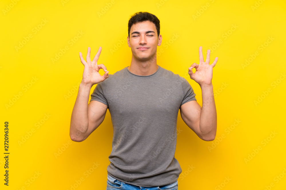 Handsome man over isolated yellow wall in zen pose Handsome man over isolated yellow wall in zen pose