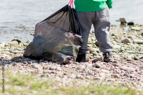 Save environment concept, a little boy collecting garbage and plastic bottles on the beach to dumped into the trash.