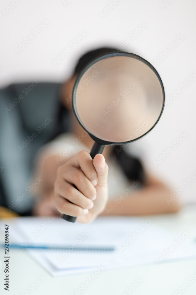 Fototapeta premium Little Asian girl using magnifier doing homework and smile with happiness for education concept select focus shallow depth of field