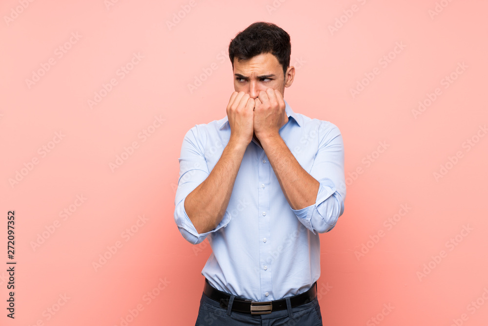 Handsome man over pink background nervous and scared putting hands to mouth Handsome man over pink background nervous and scared putting hands to mouth
