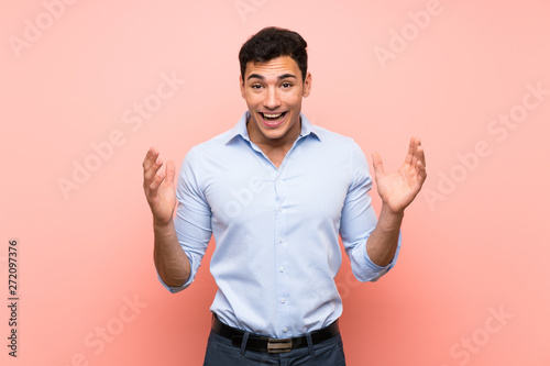 Handsome man over pink background with shocked facial expression
