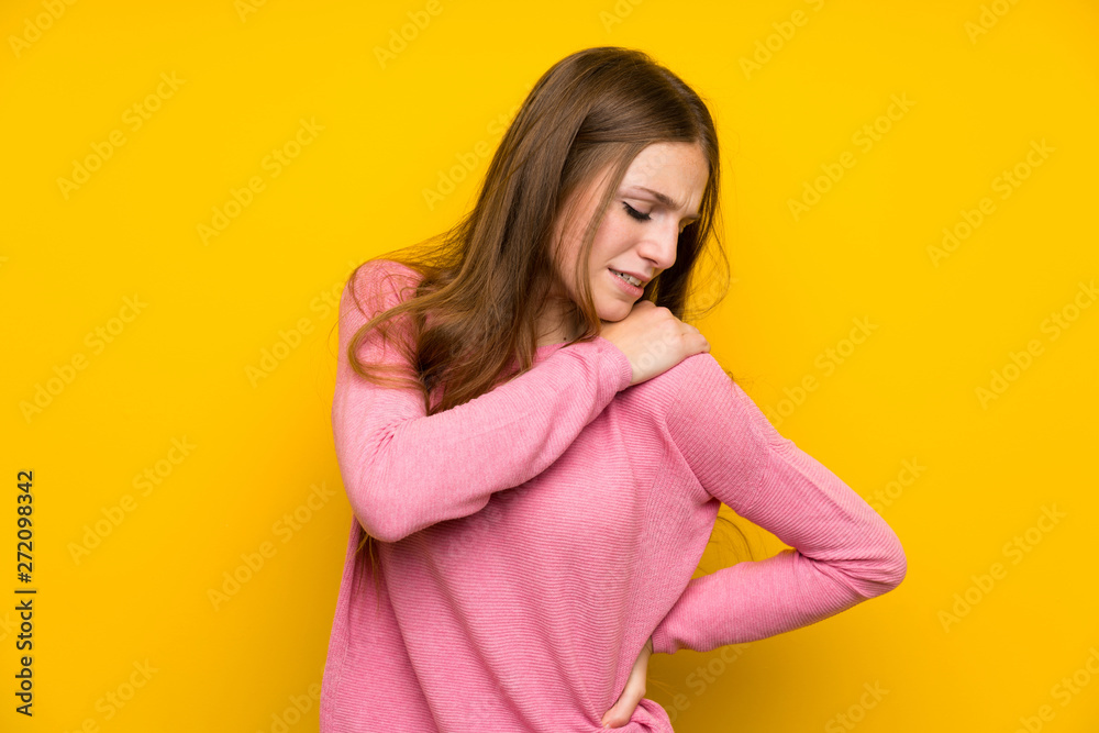 Young woman with long hair over isolated yellow wall suffering from pain in shoulder for having made an effort Young woman with long hair over isolated yellow wall suffering from pain in shoulder for having made an effort