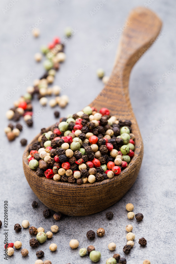Peppercorn mix in a wooden bowl on grey table. Peppercorn mix in a wooden bowl on grey table.