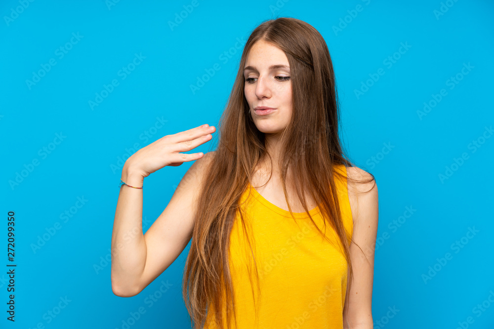 Young woman with long hair over isolated blue wall with tired and sick expression Young woman with long hair over isolated blue wall with tired and sick expression