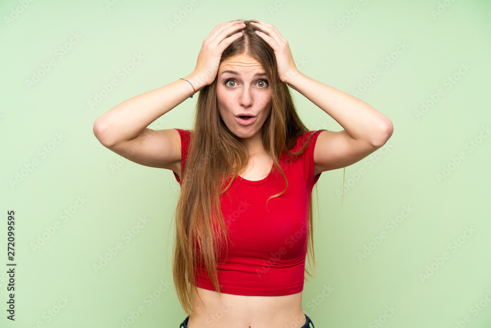 Young woman with long hair over isolated green wall with surprise facial expression Young woman with long hair over isolated green wall with surprise facial expression
