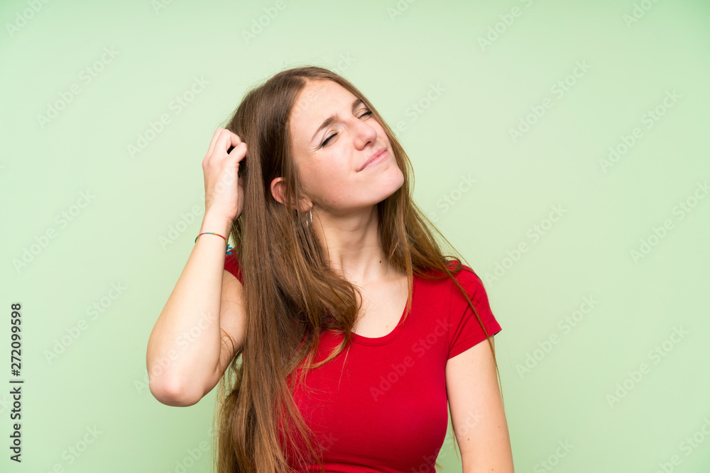 Young woman with long hair over isolated green wall having doubts and with confuse face expression
