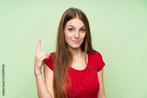 Young woman with long hair over isolated green wall pointing with the index finger a great idea
