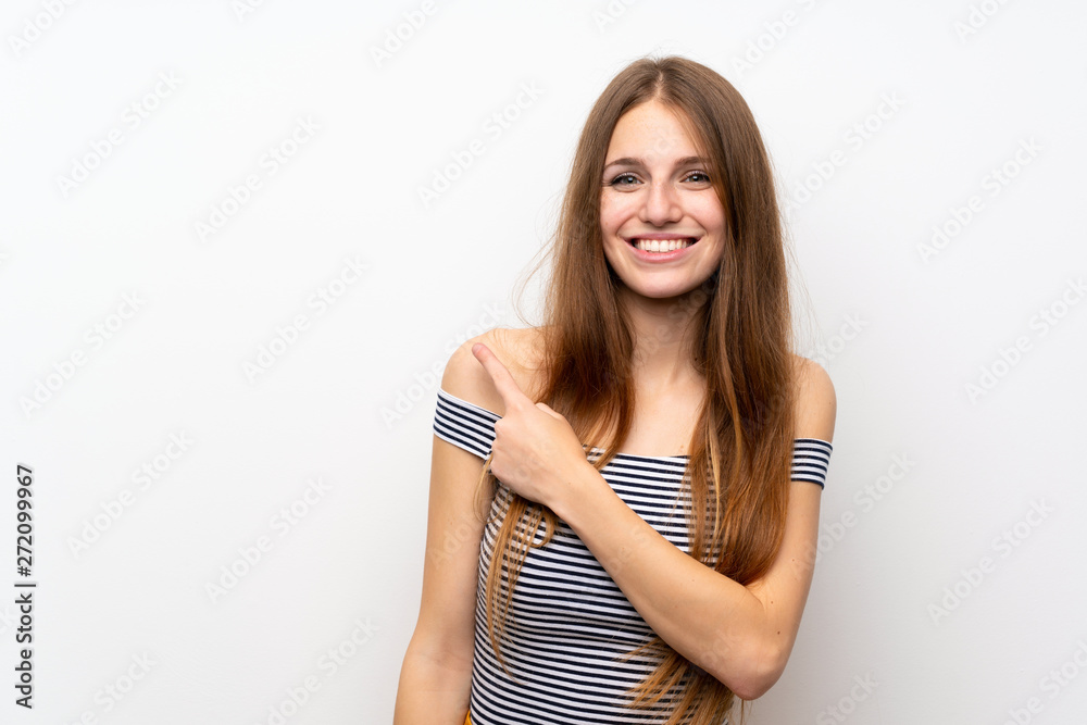 Young woman with long hair over isolated white wall pointing to the side to present a product Young woman with long hair over isolated white wall pointing to the side to present a product