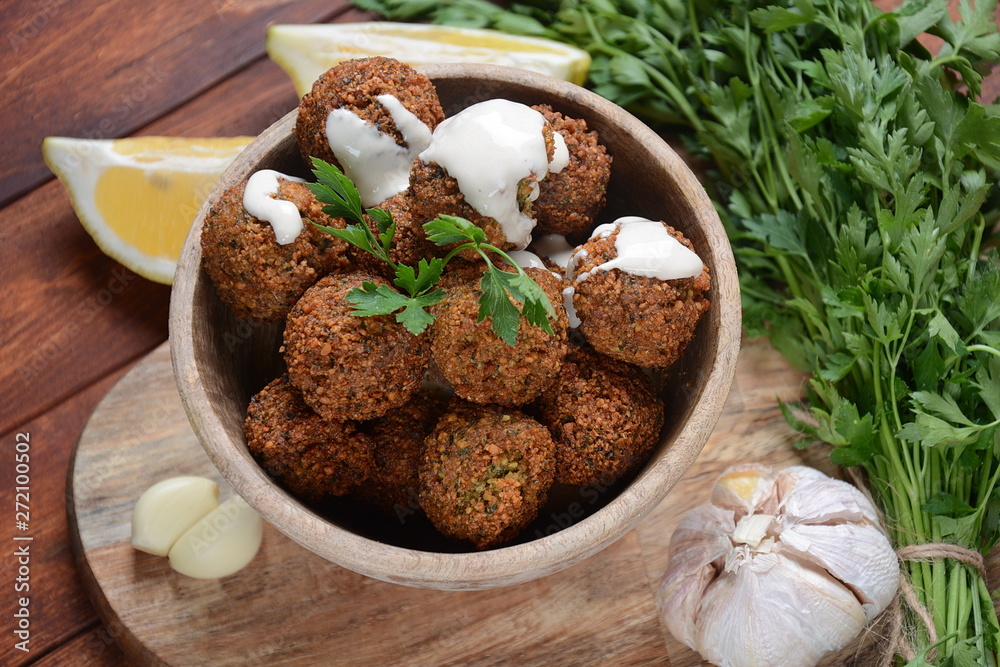 Falafel balls with parsley in wooden bowl with tahini sauce. Vegan healthy food Falafel balls with parsley in wooden bowl with tahini sauce. Vegan healthy food