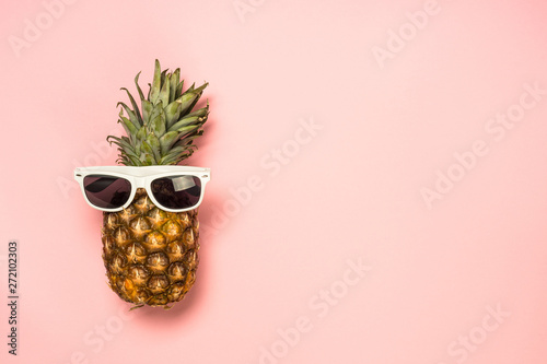 Funny pineapple in sunglasses on pink background.
