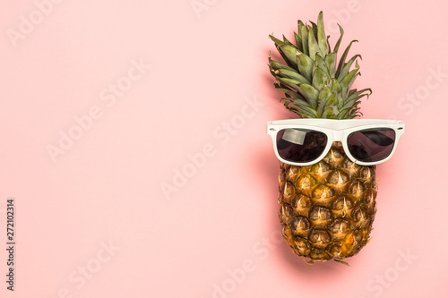 Funny pineapple in sunglasses on pink background.