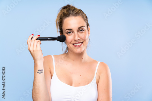 Happy Young blonde woman with makeup brush