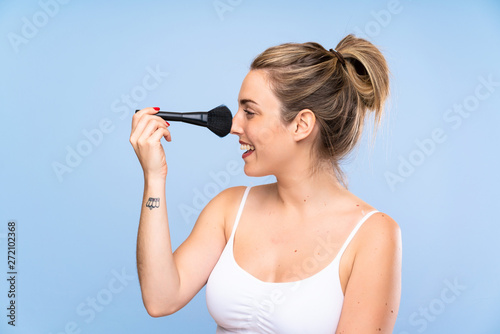 Happy Young blonde woman with makeup brush