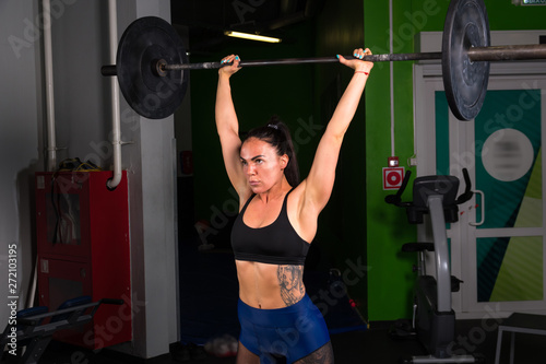 Strong muscular girl training in the gym with a barbell