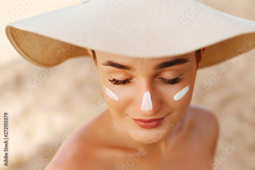 Beauty Woman smile applying sun cream on face. Skin care. Body Sun protection. sunscreen. Female in hat smear moisturizing lotion on skin