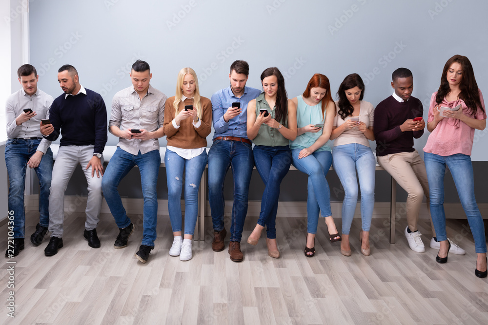 Fototapeta premium Row Of Young People Using Cellphones