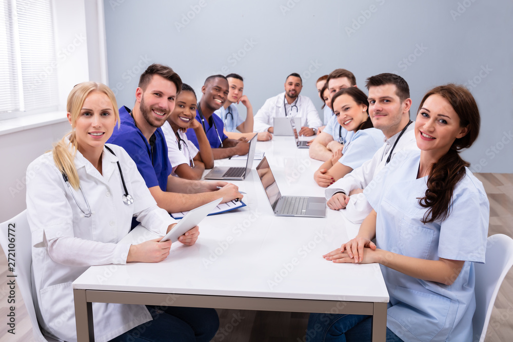 Doctors Looking At Camera While Sitting On Medical Office Doctors Looking At Camera While Sitting On Medical Office