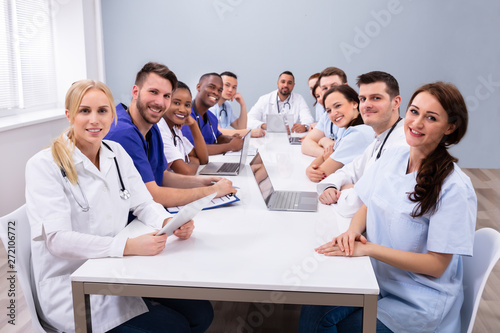 Doctors Looking At Camera While Sitting On Medical Office