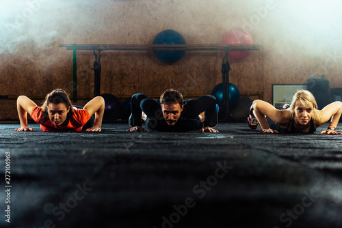 Fit young people doing pushups in a gym photo