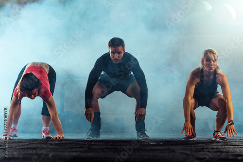 Fit young people doing squats in a gym