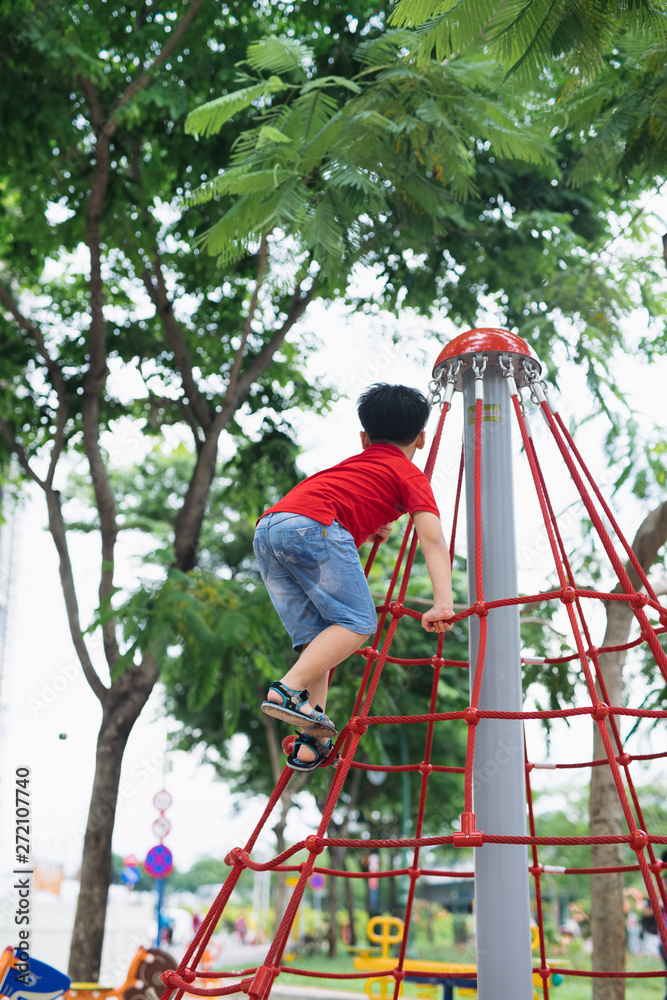 little boy playing on monkey bars at playground little boy playing on monkey bars at playground