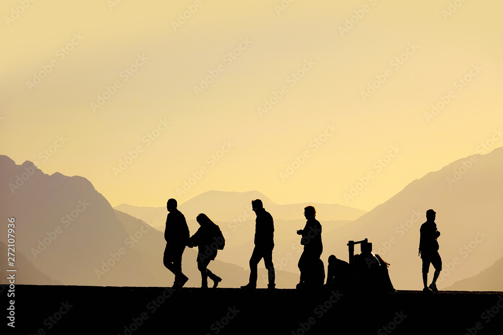Silhouetted  people walking on street over sunset sky and high mountains in Antalya, Turkey