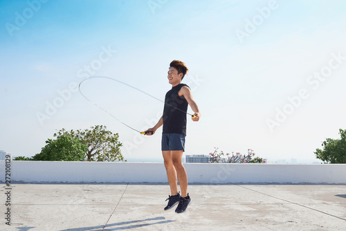 Fotografie fitness, sport, people, exercising and lifestyle concept - man skipping with jum