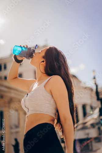 Healthy and sporty young woman drinking water from the bottle