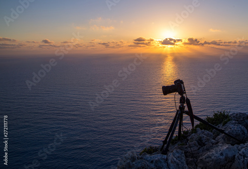 Camera on a tripod isolated in sunrise background. silhouette of camera on tripod with mountains background in sunrise, camera prepared to take photos, tripod.shooting mountains in sunset