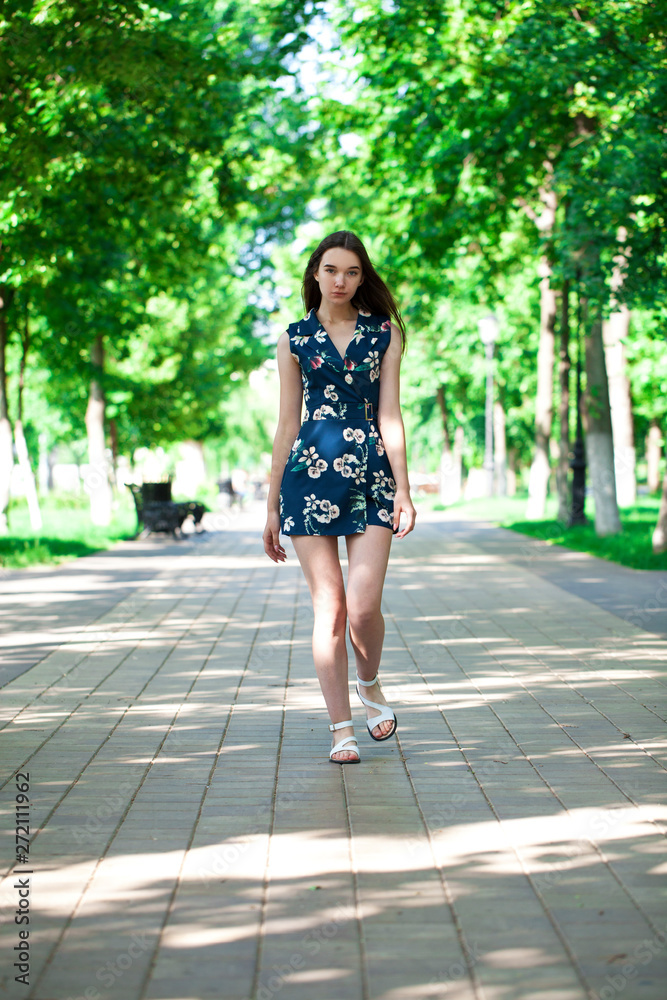 Young beautiful woman in a blue short dress walking on the road Young beautiful woman in a blue short dress walking on the road