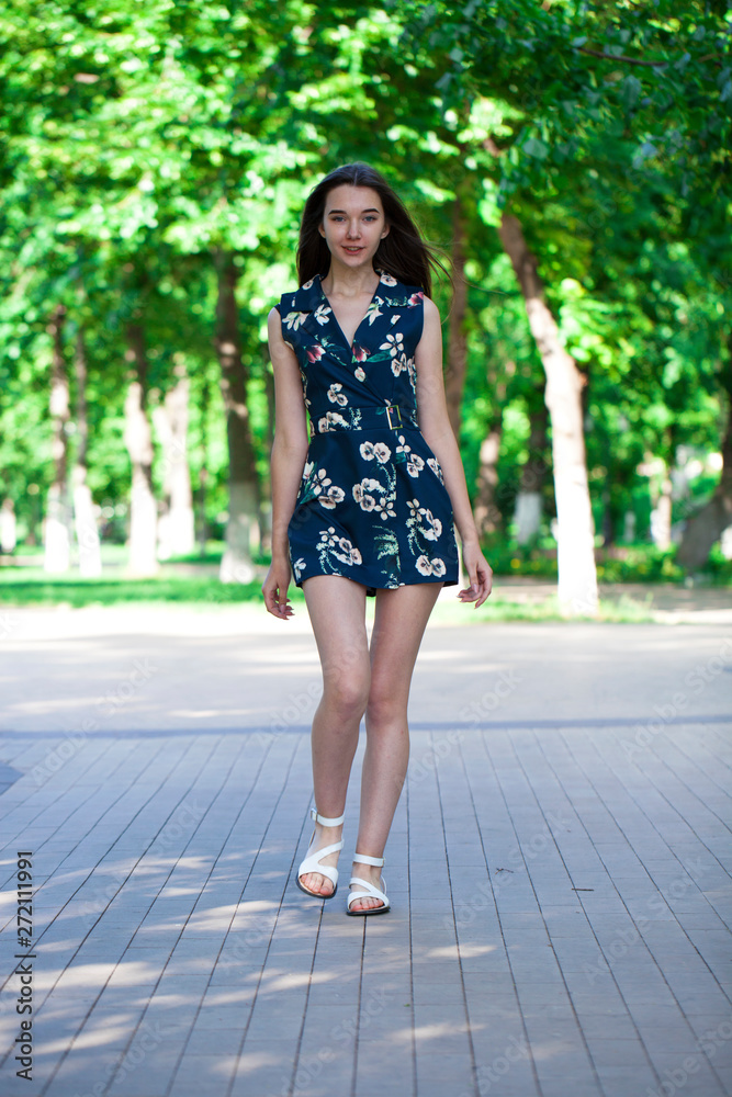Young beautiful woman in a blue short dress walking on the road Young beautiful woman in a blue short dress walking on the road