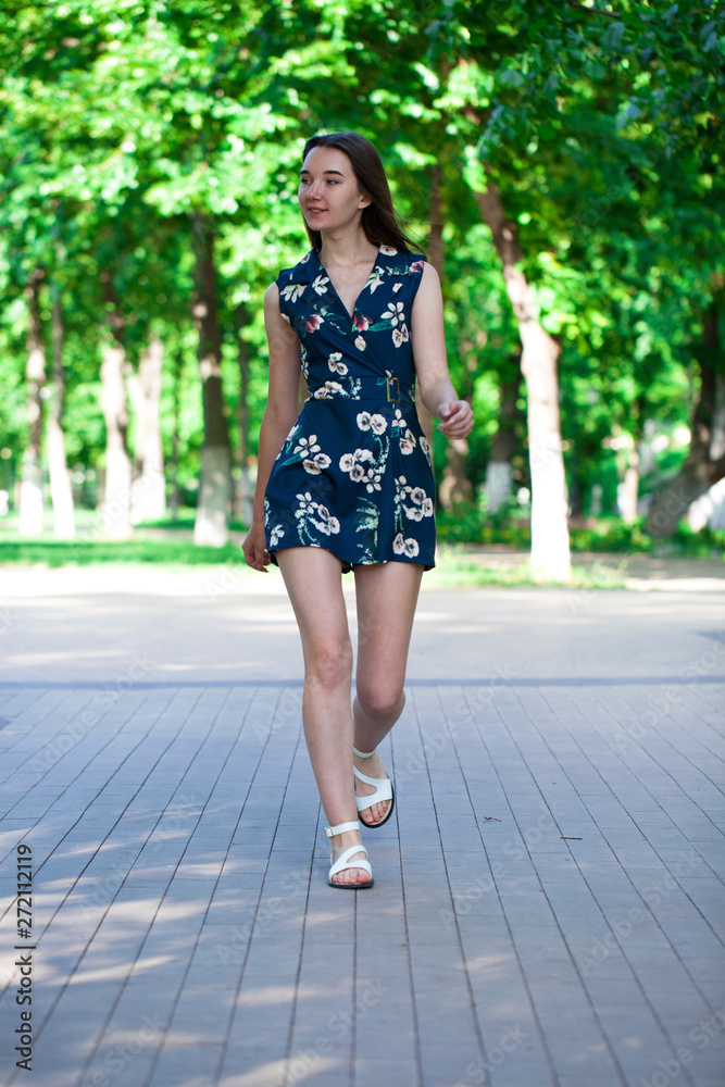 Young beautiful woman in a blue short dress walking on the road Young beautiful woman in a blue short dress walking on the road
