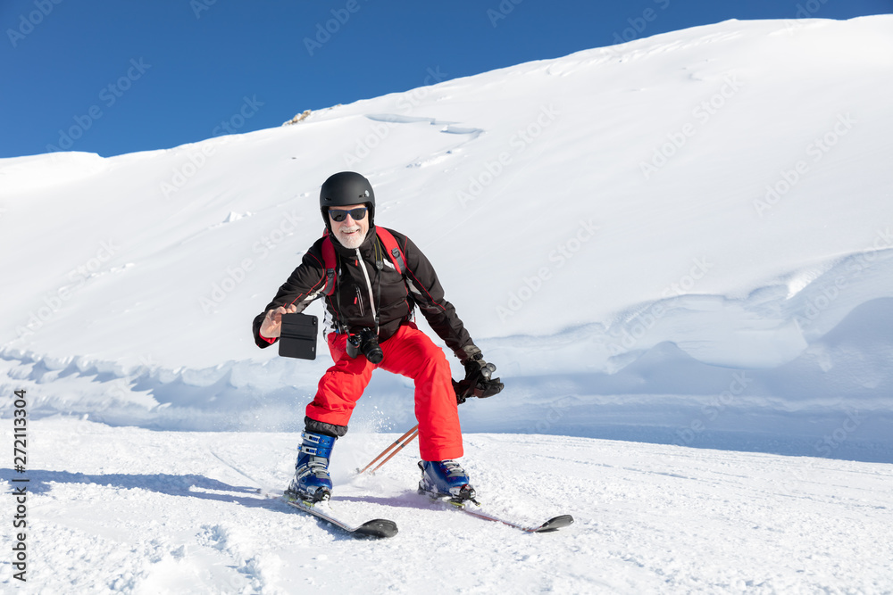 Senior skier uses his smart phone to record a video while skiing Senior skier uses his smart phone to record a video while skiing