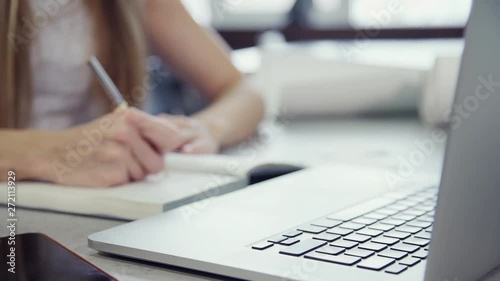 Wallpaper Mural Woman is working with laptop sitting at table checking information from notebook Torontodigital.ca