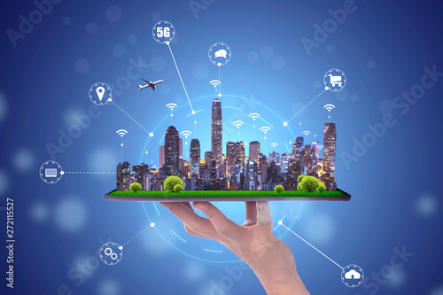 hand holding an empty digital tablet with Smart city with smart services and icons, internet of things, networks and augmented reality concept , night scape