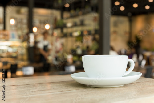 Cup of coffee on wooden table in cafe with blurred background.