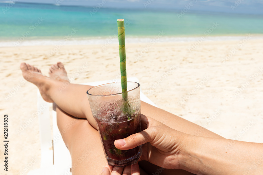 Woman Lying On Deck Chair Holding Juice Glass At Beach Woman Lying On Deck Chair Holding Juice Glass At Beach